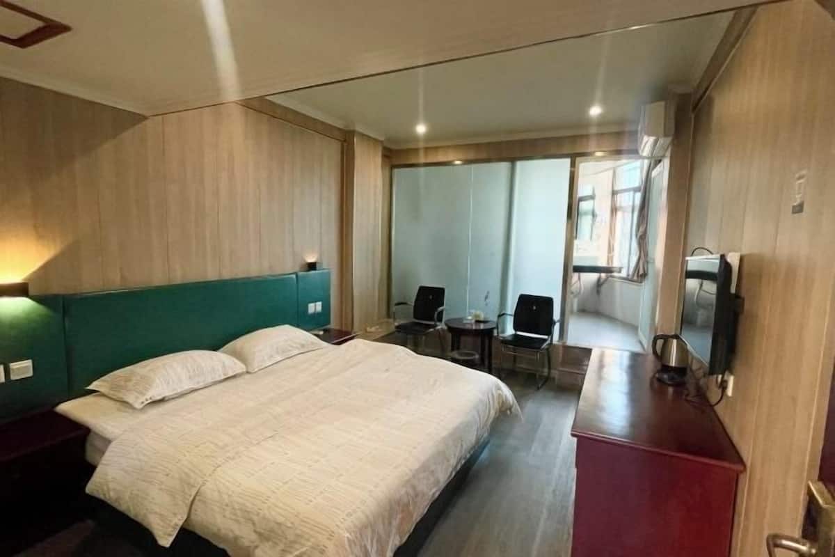 A hotel room with a large bed, a desk, a chair, and a small table.