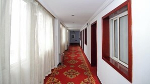 A hallway with a red carpet, white walls, and red-framed windows. - Jinkairui Hotel Lijiang (Lujiang)