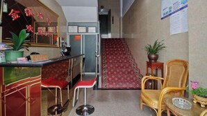 A reception area with a counter, red chairs, a staircase, and a potted plant. - Jinkairui Hotel Lijiang (Lujiang)