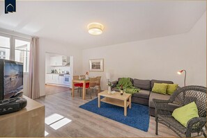 A modern living room with a TV, dining area, and a sofa. - Ferienwohnung Astrid - Moderne Parterre-ferienwohnung mit Terrasse, nah am Strand (Heringsdorf)