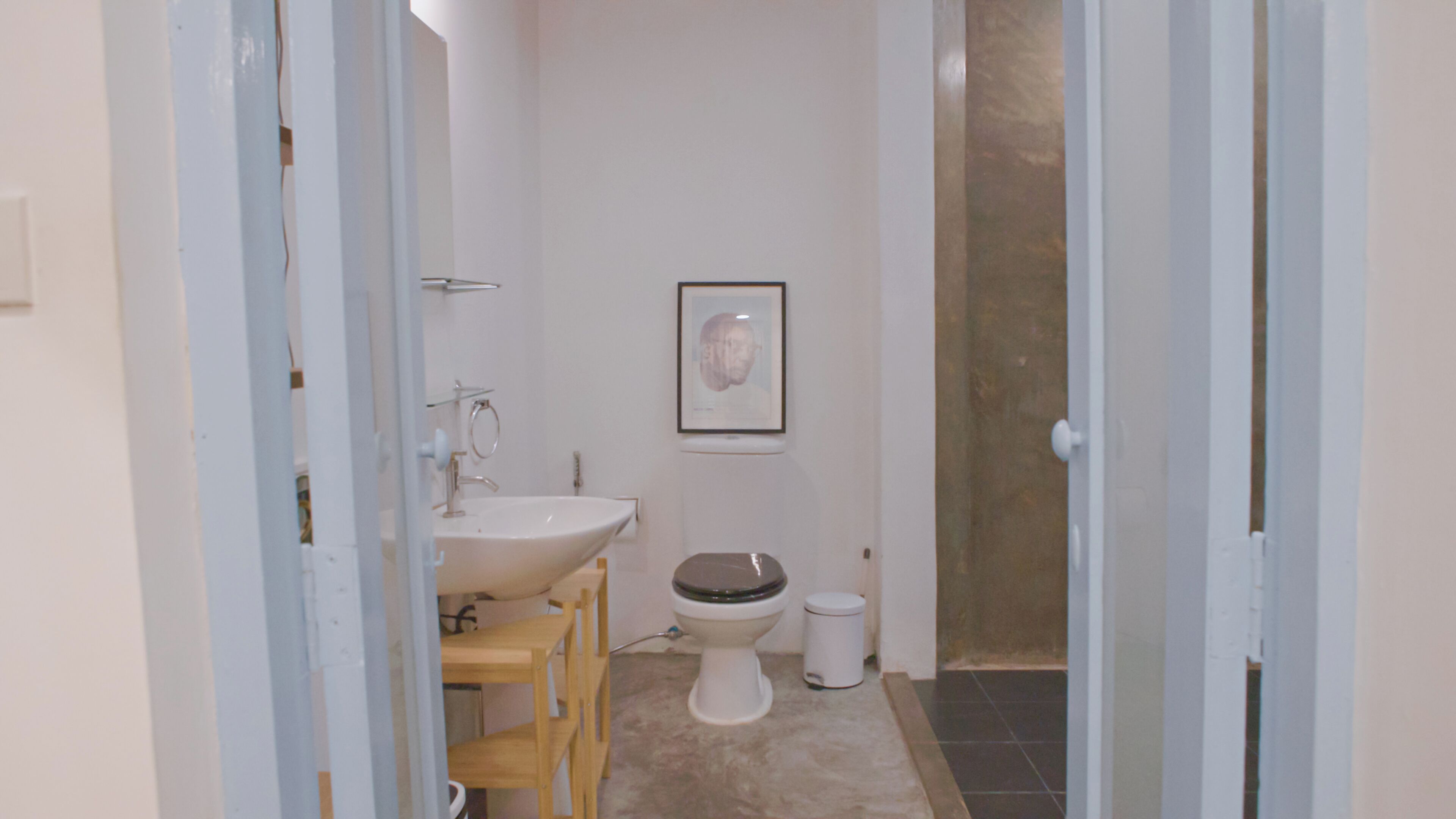 A bathroom with a sink, toilet, and a framed picture on the wall.