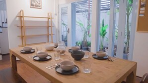 Une table à manger dressée avec des bols, des verres et des couverts, avec un banc en bois et une étagère en forme d’échelle en arrière-plan.