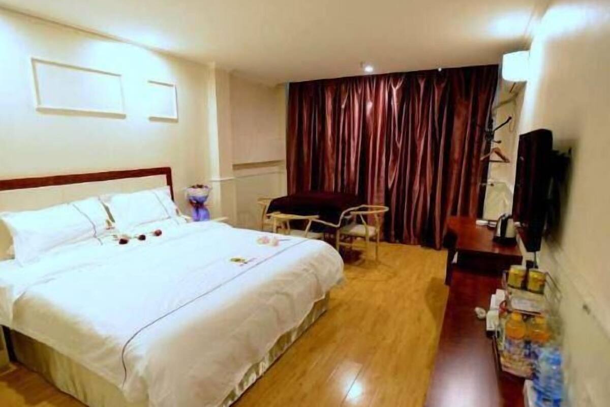 A hotel room with a bed, a desk, a chair, a television, and a curtain.