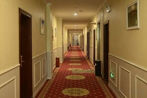 A hotel corridor with a red carpet, doors, and light fixtures. - Super 8 Hotel (Korla Tianshan West Road) (Korla)