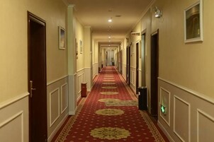 Un pasillo de hotel con alfombra roja, puertas e iluminación.