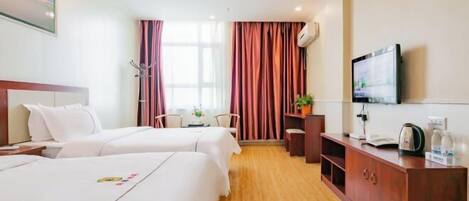 A hotel room with two beds, a desk, a TV, and a window with curtains.