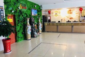 A reception area with a green wall, large vases, and a reception desk. - Super 8 Hotel (Korla Tianshan West Road) (Korla)