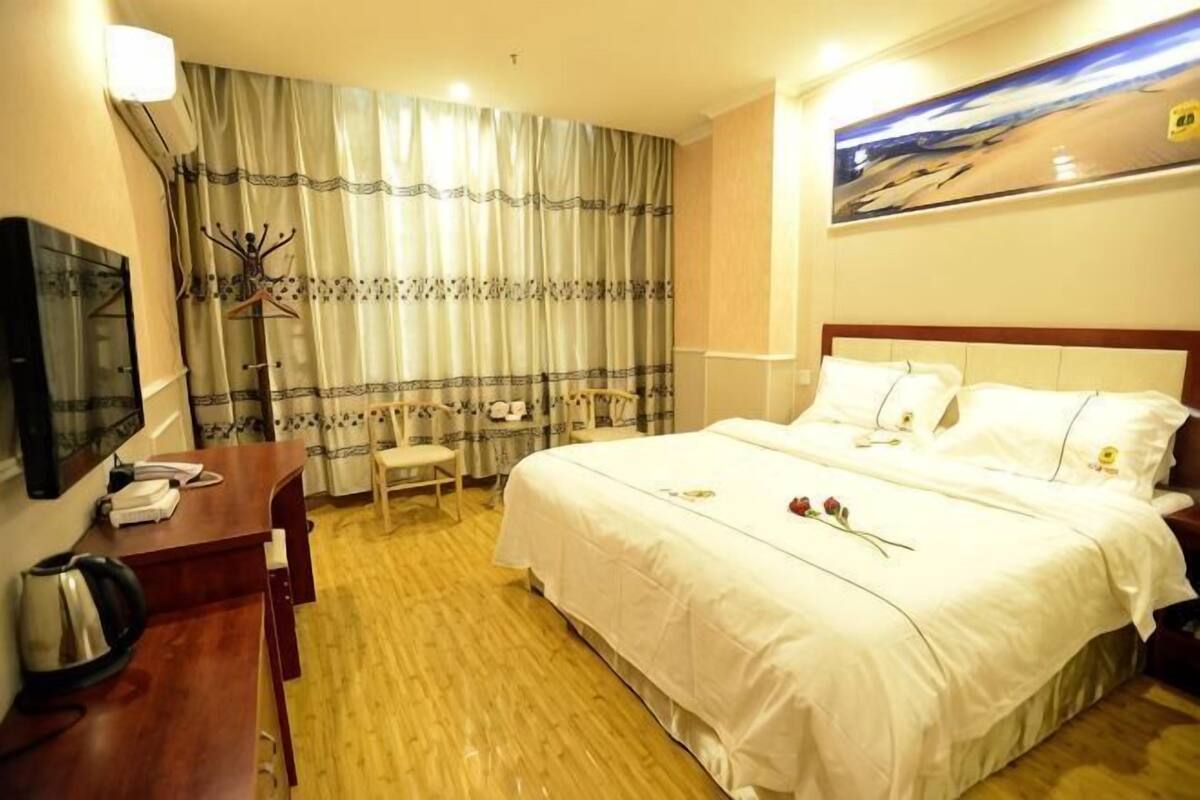 A hotel room with a bed, a desk, a chair, a television, and a painting on the wall.