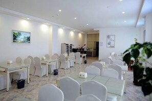 A conference room with multiple tables and chairs, a kitchen area, and a large plant. - Super 8 Hotel (Korla Tianshan West Road) (Korla)