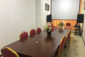 A conference room with a long table, red chairs, a vase of flowers, and a projector screen. - Super 8 Hotel (Korla Tianshan West Road) (Korla)