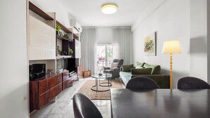A modern living room with a dining area, a sofa, a coffee table, and a TV. - Ben Yehuda Green Charm by Sea N' Rent (Tel Aviv)