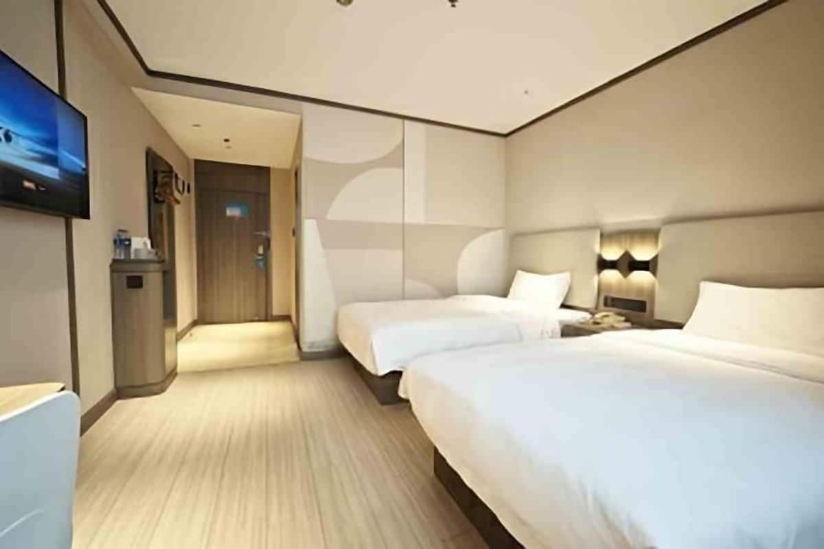 A hotel room with a large bed, a smaller bed, a TV, a desk, and a bathroom.