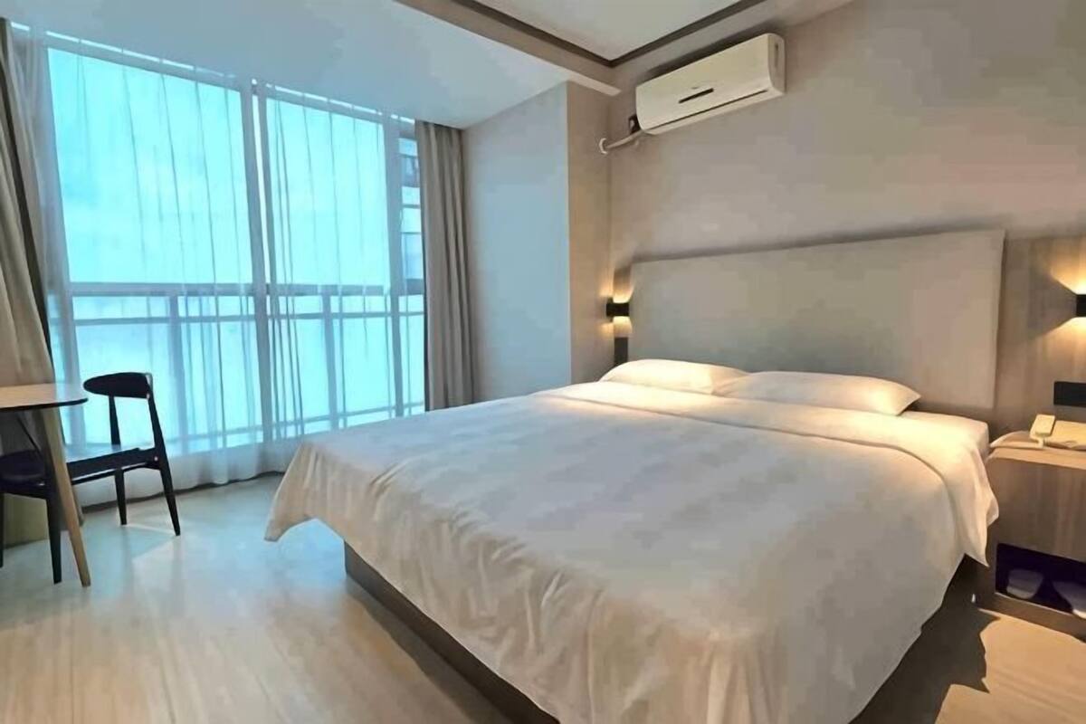 A hotel room with a large bed, a desk, and a chair.