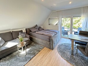 Une chambre moderne avec un canapé, un lit, une petite table et une vue sur l’extérieur.