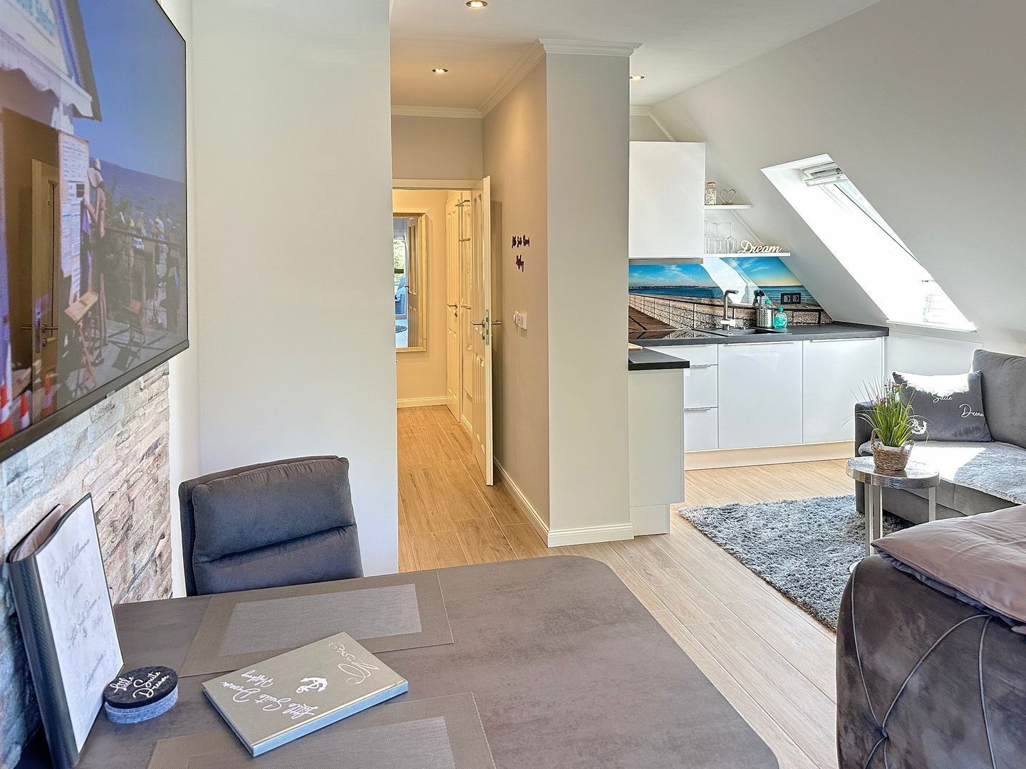 A modern apartment with a dining area, a kitchen with a skylight, and a living room with a sofa and a coffee table.