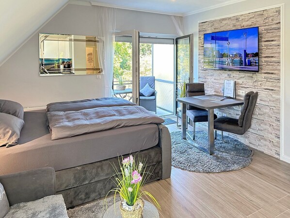Une chambre moderne avec un lit, un coin repas et un téléviseur fixé au mur.