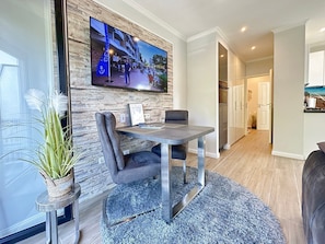 A modern dining area with a stone accent wall, a flat-screen TV, and a view of the outdoors.