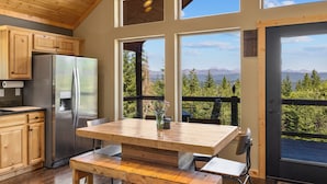 A modern kitchen with wooden cabinets, a stainless steel refrigerator, and a large dining table with benches.