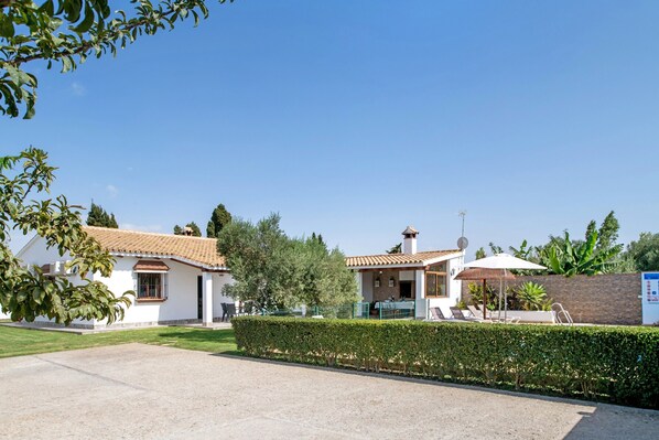 Une maison à deux étages, avec un toit recouvert de tuiles, une allée pavée et une pelouse bien entretenue.