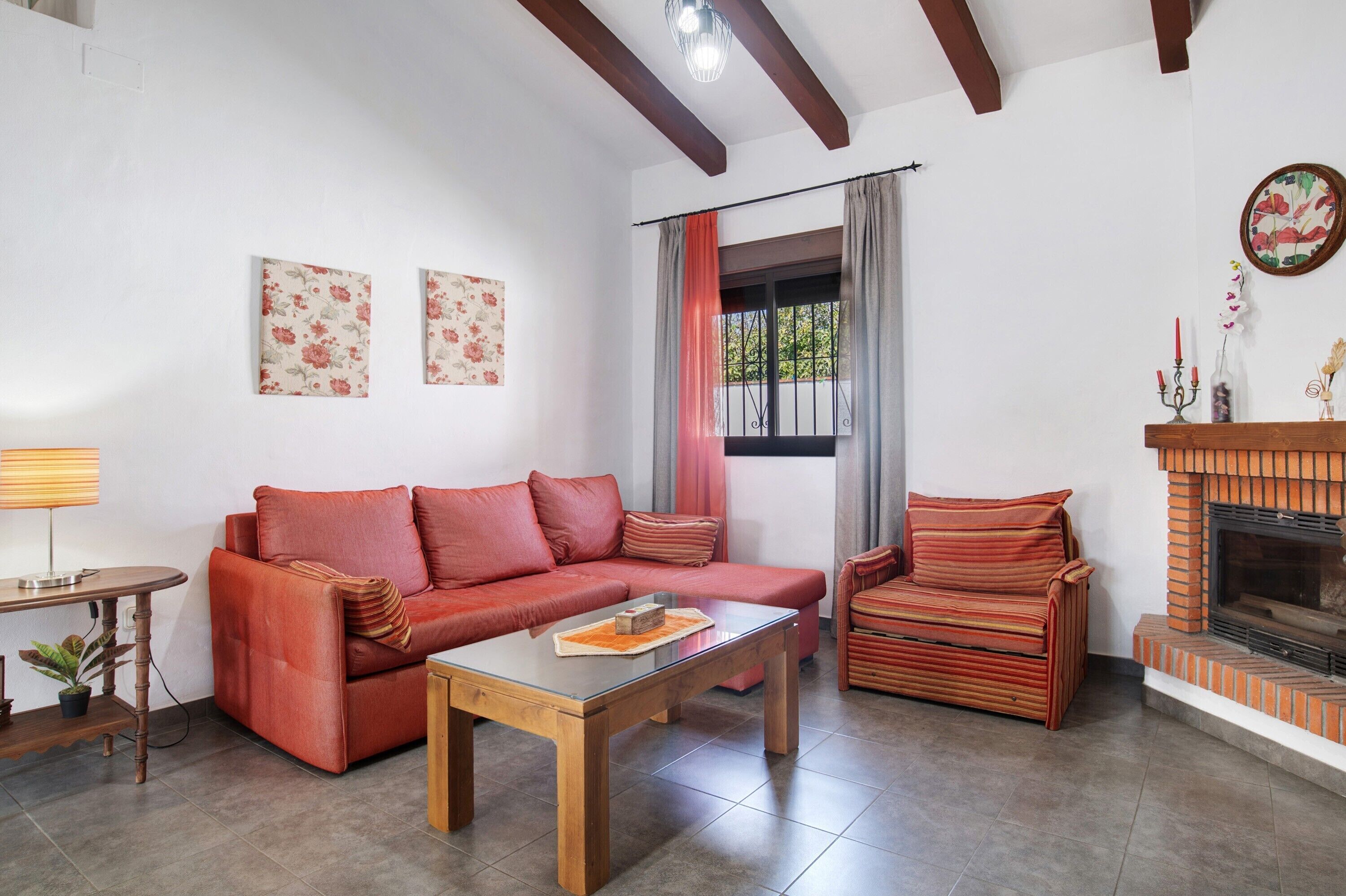 A living room with a sofa, a coffee table, a fireplace, and a window with curtains.