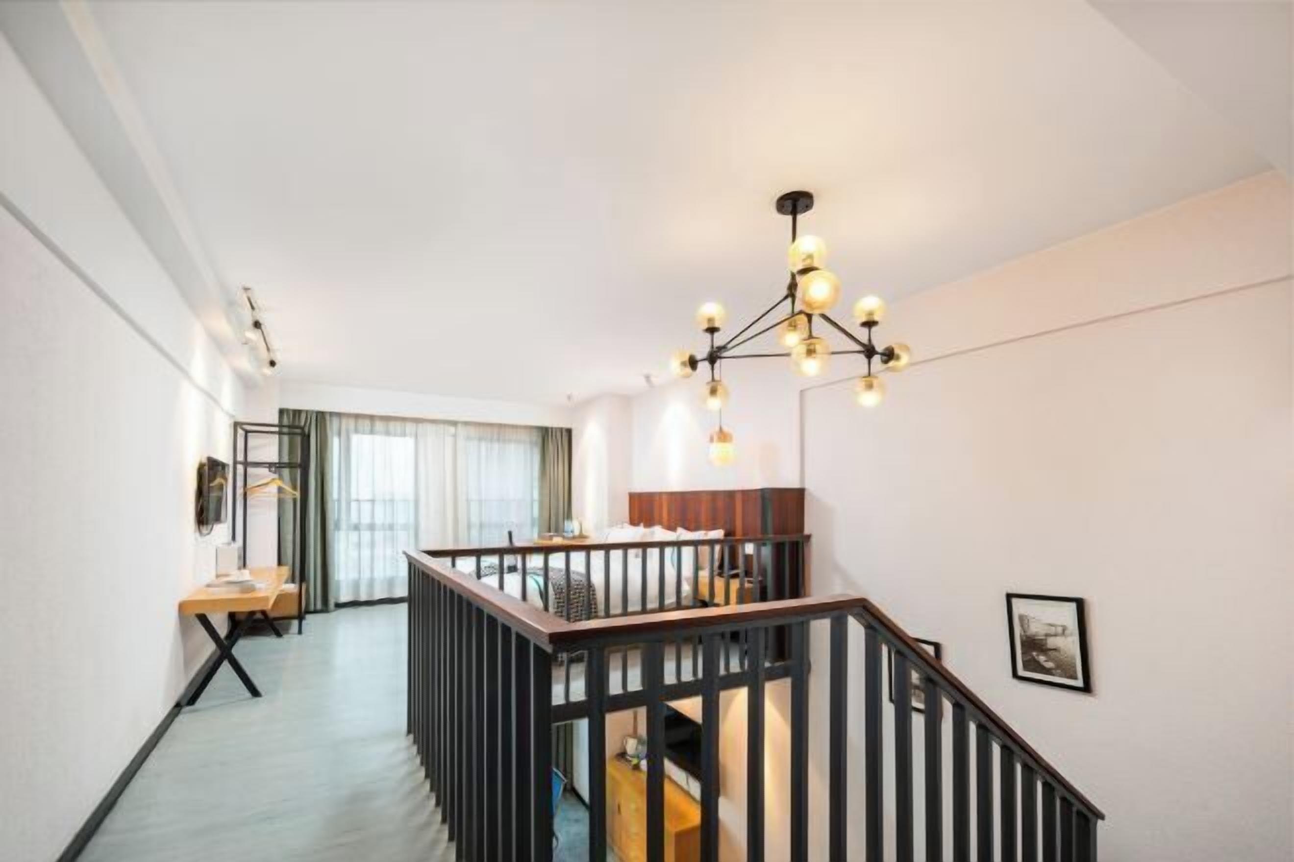 A modern interior with a staircase, a hanging light fixture, and a view to another room.