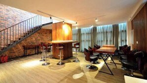 A modern bar area with a wooden counter, bar stools, and a staircase leading to an upper level. - Jingkaisi Hotel (Taojialing Subway Station Renxinhui Branch) (Wuhan)