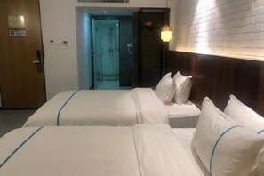 A hotel room with two beds, a wooden headboard, a wall-mounted lamp, and a door with a sign. - Jingkaisi Hotel (Taojialing Subway Station Renxinhui Branch) (Wuhan)