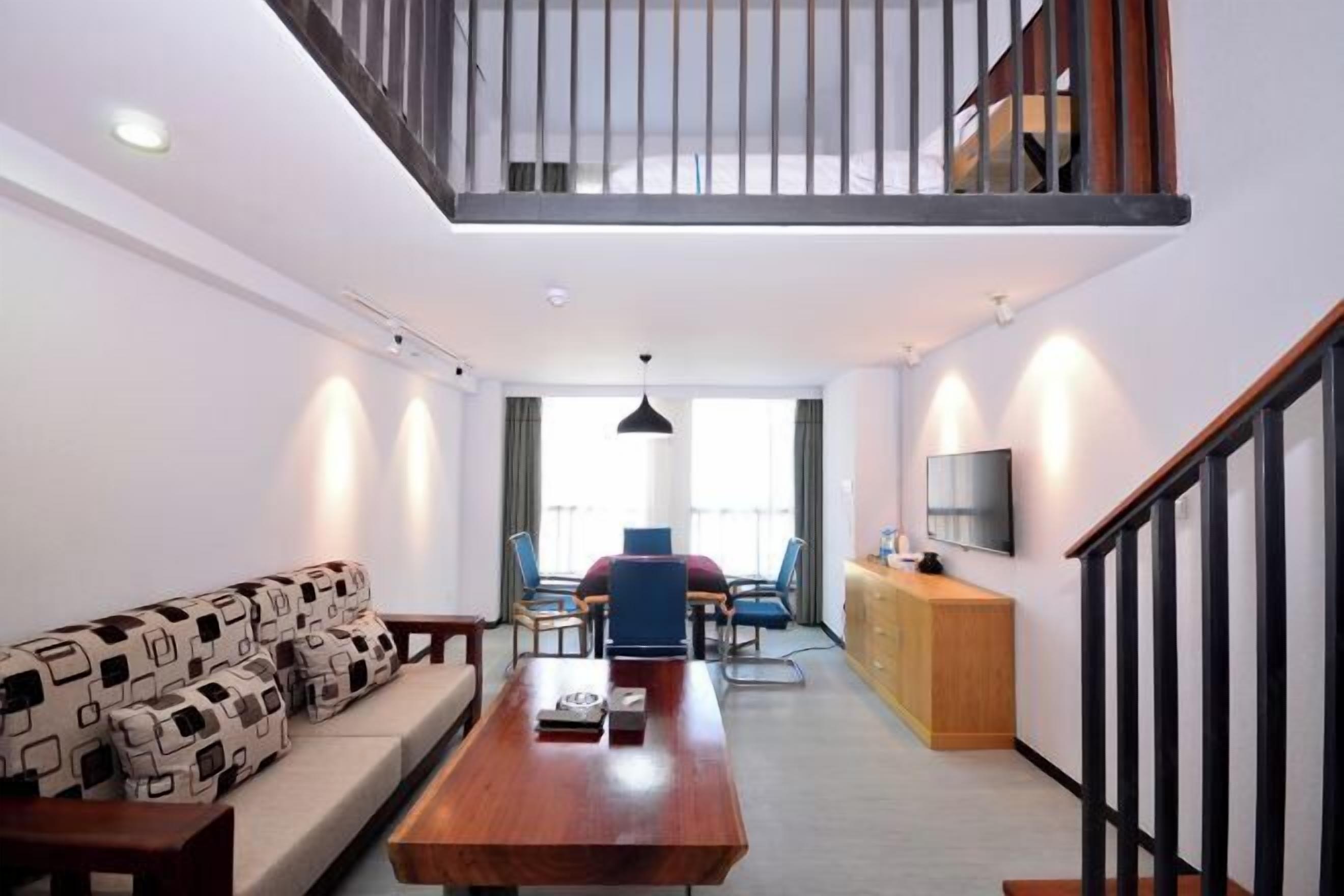 A modern living room with a sofa, a wooden coffee table, a TV, and a staircase.