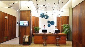 A reception desk with two monitors, a television, and a wooden wall with decorative plates. - Jingkaisi Hotel (Taojialing Subway Station Renxinhui Branch) (Wuhan)