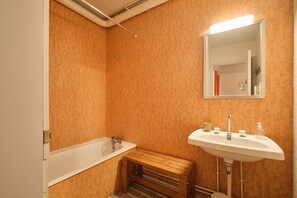 Un bagno con una vasca, una panca in legno, un lavandino e uno specchio.