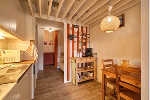 Una cucina con microonde, forno e tavolo di legno con sedie.