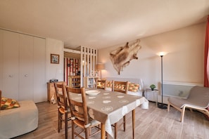 Un coin repas avec une table dressée pour quatre personnes, des chaises en bois, un canapé et un élément décoratif en fourrure accroché au mur.