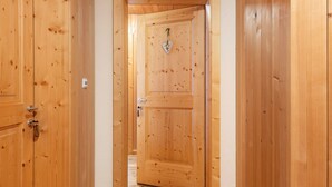 A wooden door with a heart-shaped ornament and a keyhole, leading to a room with a wooden floor.