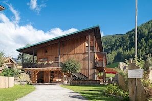 A wooden building with a balcony, a sign, and a pathway leading to it.