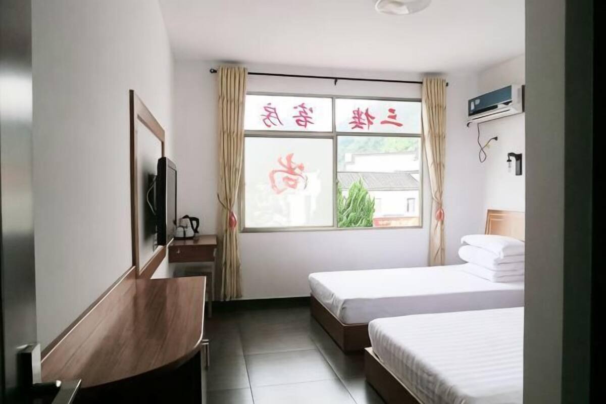 A hotel room with a bed, a desk, a TV, and a window with curtains.