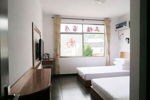 A hotel room with a bed, a desk, a TV, and a window with curtains. - Jixi Shangshufu Inn (Jixi)