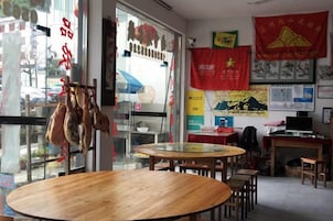 Interior de restaurante con mesas redondas, sillas, una mesa de comedor de madera y vistas por la ventana.