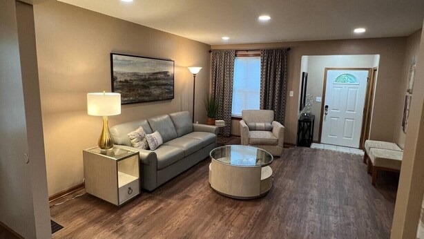 A living room with a sofa, armchair, coffee table, lamp, and a painting on the wall.