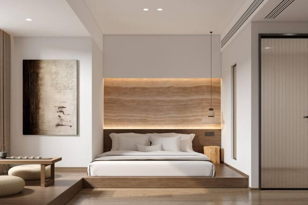 Ein modernes Schlafzimmer mit einem großen Bett, einem Kopfteil aus hellem Holz, einem Nachttisch und einem an der Wand befestigten Kunstwerk.