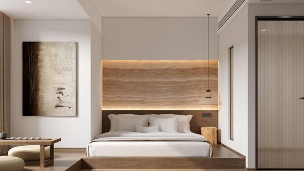 A modern bedroom with a large bed, a headboard with a light wood finish, a bedside table, and a wall-mounted artwork.