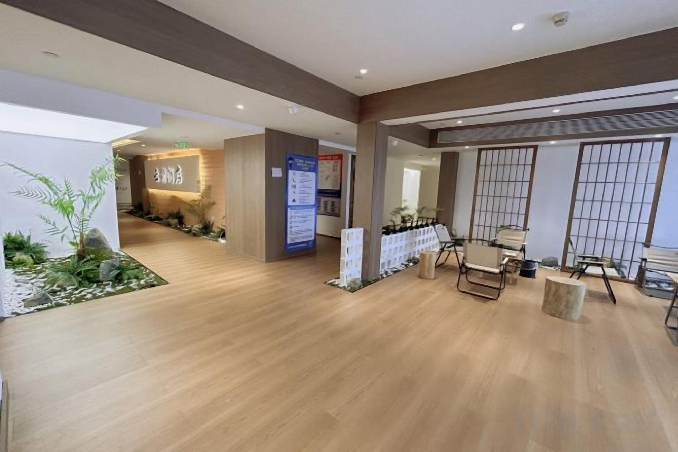 Un hall de hotel con suelo de madera, mostrador de recepción, zona de estar y vistas al exterior.