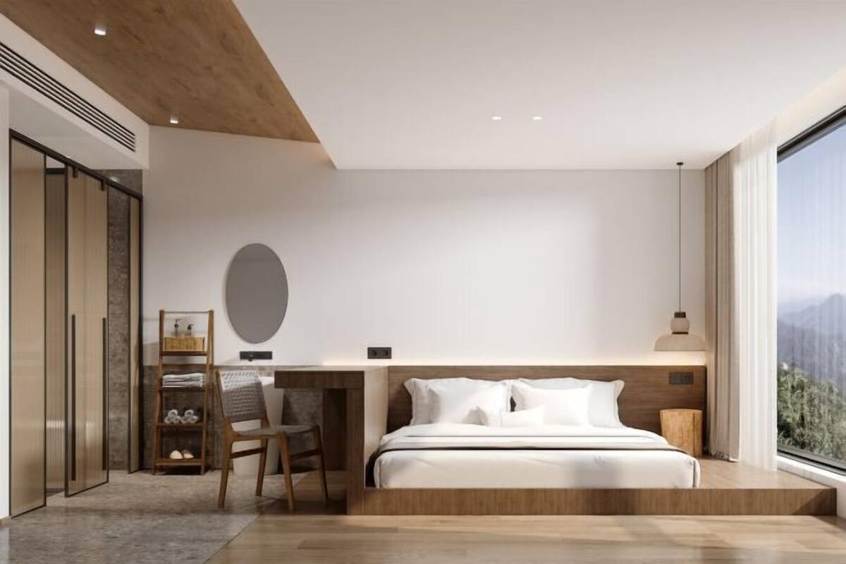 Ein modernes Schlafzimmer mit Bett, Schreibtisch und Stuhl, einem großen Fenster mit Aussicht und einer Holzbalkendecke.