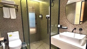 A modern bathroom with a glass-enclosed shower, a white sink, and a toilet.