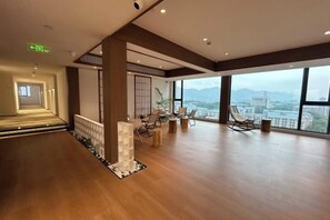 A spacious hotel lobby with a wooden floor, a reception desk, seating area, and large windows offering a city view. - Bozun Hotel Chongqing University City (Chongqing)