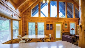 A wooden cabin interior with a dining area, a sofa, and a fireplace. - Family Cabin with Hot Tub, Game Room & Pool Access (Pigeon Forge)
