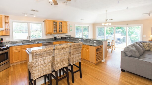 A spacious kitchen with a large island, wooden cabinets, and a dining area with wicker chairs. - Three Mermaids- New Listing Walk 2 Beach, Pool, Waterfront (Virginia Beach)