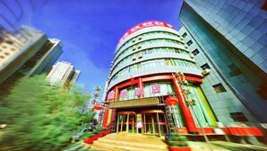 A multi-story hotel with a curved facade, large windows, and a prominent red sign at the top. - Xinranlin Hostel (Urumqi)