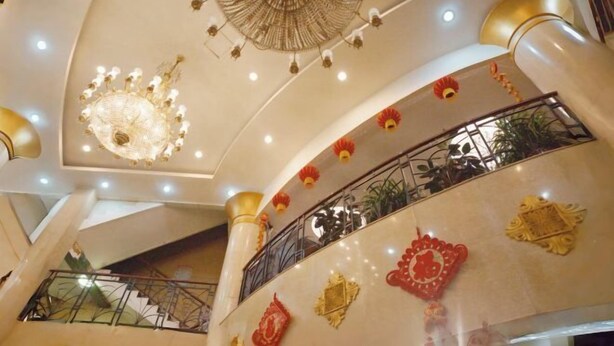A multi-level interior with a grand chandelier, decorative wall elements, and a balcony with railings. - Xinranlin Hostel (Urumqi)
