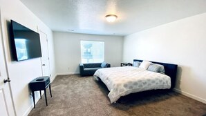 Quarto com cama, televisão, mesa pequena e janela.