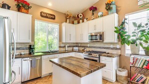 A modern kitchen with white cabinets, a central island, stainless steel appliances, and decorative flowers.